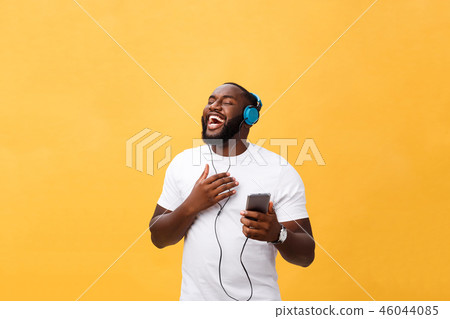 African American man with headphones listen and dance with music. Isolated on yellow background African American man with headphones listen and dance with music. Isolated on yellow background 46044085