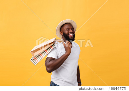Happy african american man holding shopping bags on yellow background. Holidays concept 46044775