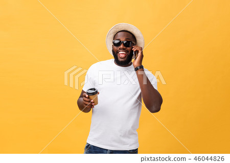 Handsome African American with mobile phone and take away coffee cup. Isolated over yellow gold Handsome African American with mobile phone and take away coffee cup. Isolated over yellow gold 46044826