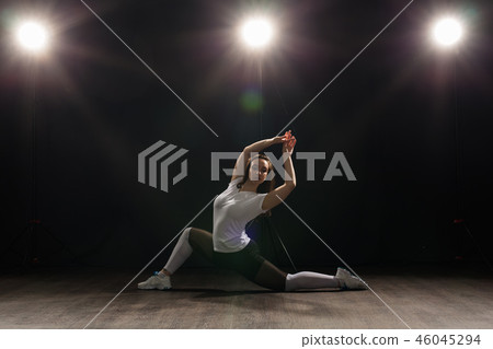 Young beautiful slim woman dancing jazz-funk on a black studio background Young beautiful slim woman dancing jazz-funk on a black studio background 46045294