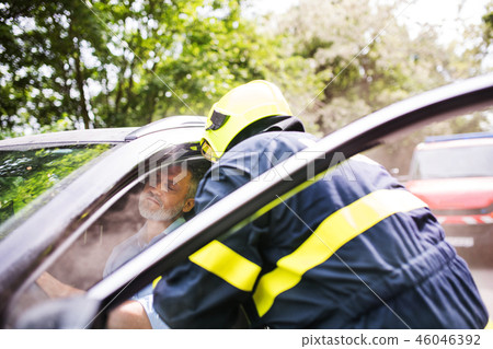A firefighter getting an unconscious man out of the car after an accident. A firefighter getting an unconscious man out of the car after an accident. 46046392