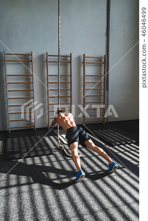 Fit young man in gym working out with climbing rope. Fit young man in gym working out with climbing rope. 46046499