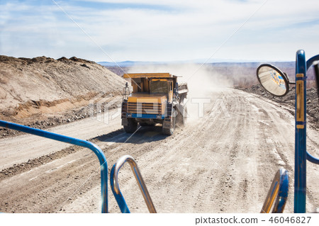 Old yellow dump truck moving in a mine 46046827