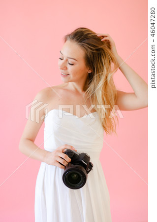 Young cute female photographer with camera in pink monophonic background. Young cute female photographer with camera in pink monophonic background. 46047280
