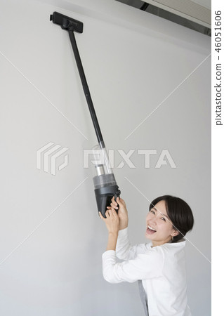 Housewife cleans the ceiling with a light vacuum cleaner Housewife cleans the ceiling with a light vacuum cleaner 46051606