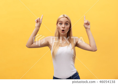 Surprised young woman wearing white clothes while looking at camera isolated on yellow background. Surprised young woman wearing white clothes while looking at camera isolated on yellow background. 46054138