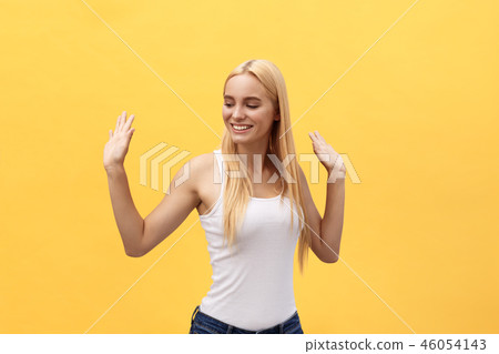 Portrait of a cheerful happy girl student while dancing isolated over yellow background 46054143