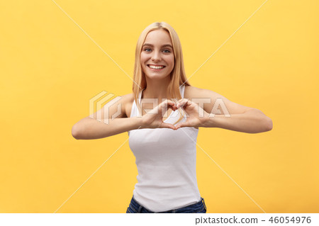 Portrait of a smiling young caucasian woman showing heart gesture with two hands and looking at Portrait of a smiling young caucasian woman showing heart gesture with two hands and looking at 46054976
