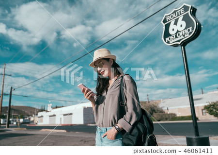 woman using cellphone standing on quiet road. woman using cellphone standing on quiet road. 46061411