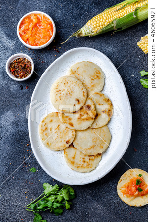 COLOMBIAN FOOD. Maize AREPAS and fried pork chicharron ans colombian tomato sauce. Top view. Black 46065921