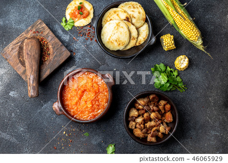 COLOMBIAN traditional food. Chicharron, maize arepas with tomato and onion sauce. Top view 46065929