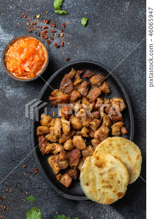 COLOMBIAN FOOD. Fried pork CHICHARRON, AREPAS and colombian tomato sauce. Top view. Black background 46065947