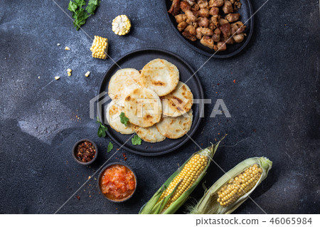 COLOMBIAN FOOD. Maize AREPAS and fried pork chicharron ans colombian tomato sauce. Top view. Black 46065984