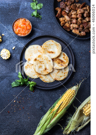 COLOMBIAN FOOD. Maize AREPAS and fried pork chicharron ans colombian tomato sauce. Top view. Black COLOMBIAN FOOD. Maize AREPAS and fried pork chicharron ans colombian tomato sauce. Top view. Black 46066014