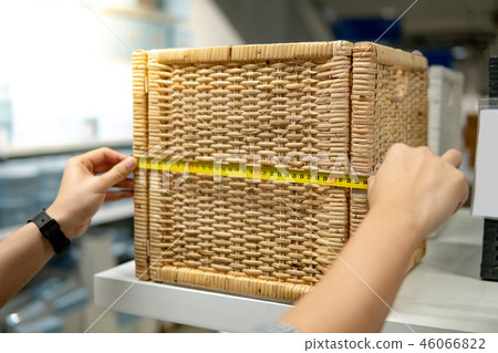 Male hand using tape measure on wooden woven box 46066822