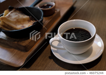 A cup of coffee and pancakes in a cast iron pan. A cup of coffee and pancakes in a cast iron pan. 46075244