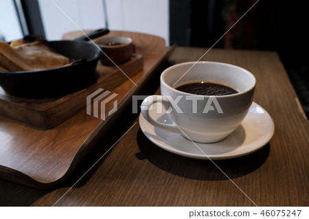 A cup of coffee and pancakes in a cast iron pan. A cup of coffee and pancakes in a cast iron pan. 46075247