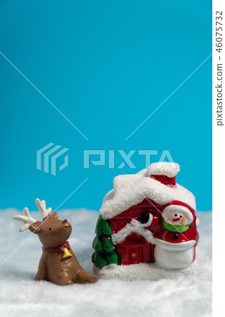 Brown reindeer siting on the snow near Snowman 46075732