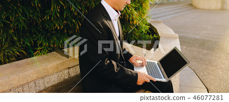 Businessman working with laptop outside near plant in  . 46077281