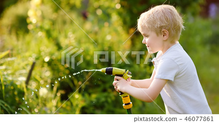 Funny little boy playing with garden hose 46077861