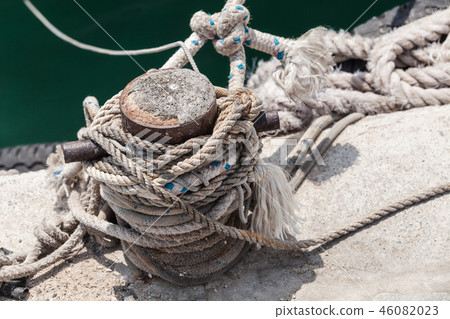 Old rusted mooring bollard with naval ropes Old rusted mooring bollard with naval ropes 46082023