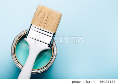 Brush on open can of turquoise paint on blue pastel background. 46085411