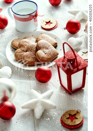 Christmas plate with homemade gingerbreads snowflakes baubles and lantern on a silver-plated table. Christmas plate with homemade gingerbreads snowflakes baubles and lantern on a silver-plated table. 46089205