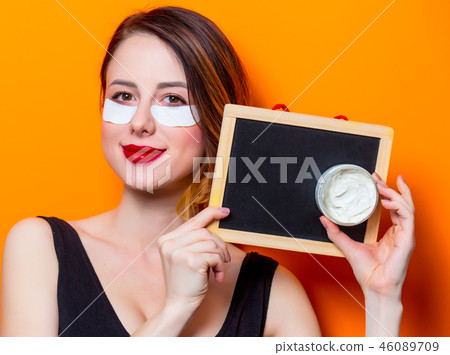 Woman using eye patch for her eyes and holding blackboad and cream Woman using eye patch for her eyes and holding blackboad and cream 46089709