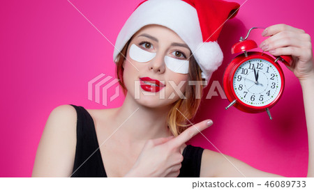 Woman using eye patch for her eyes in Santa Claus hat with alarm clock Woman using eye patch for her eyes in Santa Claus hat with alarm clock 46089733