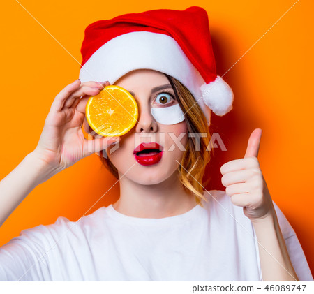Woman using eye patch for her eyes in Santa Claus hat with cytrus Woman using eye patch for her eyes in Santa Claus hat with cytrus 46089747