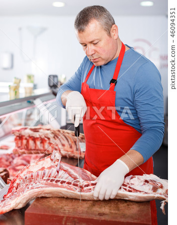 Serious seller splitting of pig carcass in shop Serious seller splitting of pig carcass in shop 46094351