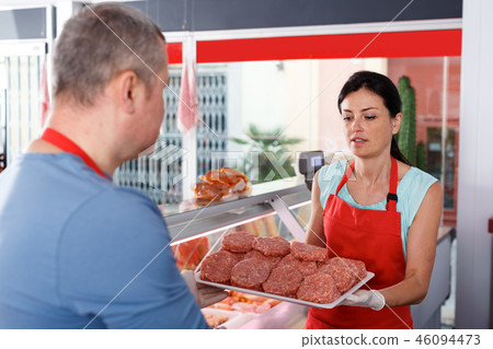 Female and male sellers showing food in shop Female and male sellers showing food in shop 46094473