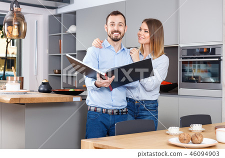 Young beautiful couple standing with book in modern kitchen interior 46094903
