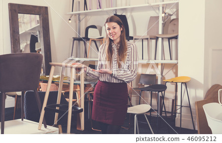 Saleswoman offering bar stools in furniture store 46095212