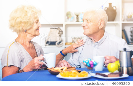 Smiling elderly spouses enjoying tea with sweets 46095260