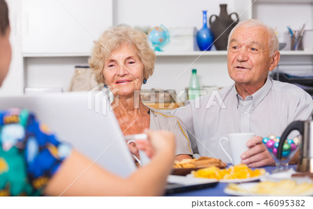 Young woman showing elderly couple something on laptop Young woman showing elderly couple something on laptop 46095382