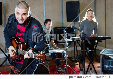 Guy guitar player and singer practicing with band members in recording studio 46095491
