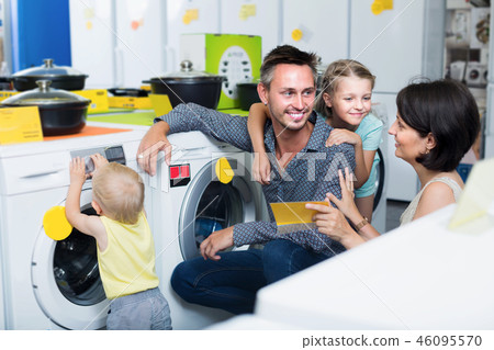 Smiling parents with kids shopping modern washer 46095570