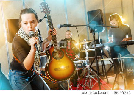 Attractive female soloist playing guitar and singing with her mu Attractive female soloist playing guitar and singing with her mu 46095755