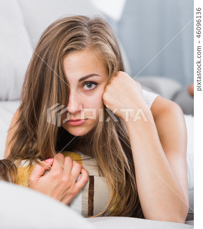 Offended girl lying on sofa with pillow 46096136