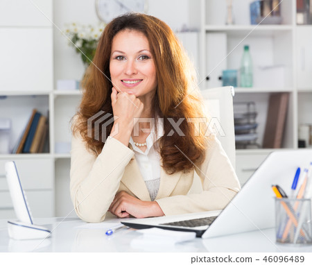Portrait of businesswoman who is working with documents behind laptop 46096489