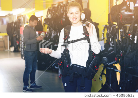 Female is standing with modern diving vest in the store. 46096632