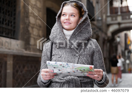 cheerful girl with map in coat hood 46097079