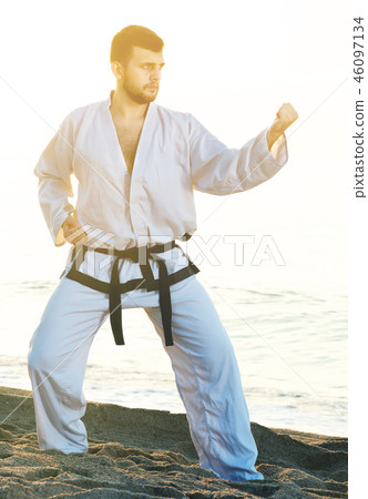 male practising karate poses at seaside 46097134