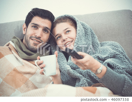 Loving couple snuggling on sofa watching TV Loving couple snuggling on sofa watching TV 46097338