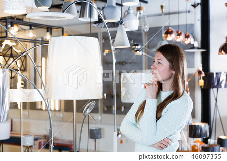 Portrait of cheerful girl buyer choosing floor lamp Portrait of cheerful girl buyer choosing floor lamp 46097355