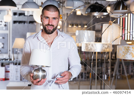 Portrait of man choosing bedside lamp in showroom 46097454