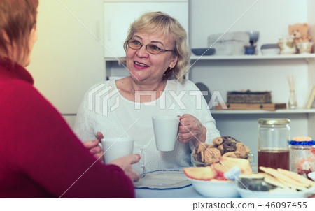 Happy senior woman with female friend over cup of coffee Happy senior woman with female friend over cup of coffee 46097455