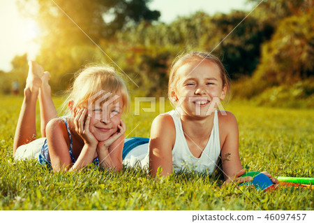 Two sisters resting on green grass Two sisters resting on green grass 46097457