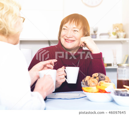 Positive old women drinking tea at the table 46097645